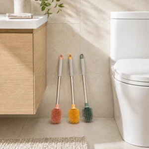 Three colorful TPR toilet brushes hanging from wall hooks beside a toilet