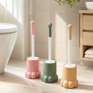 Pink and yellow cute paw toilet brushes stored beside a toilet in a bathroom
