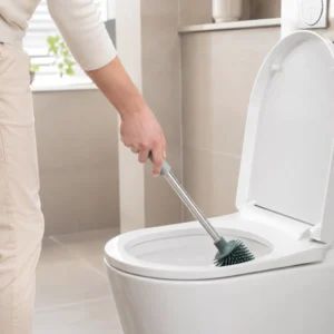 Woman using an ergonomic long handle TPR brush to clean a toilet